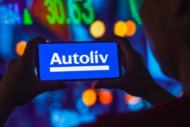 11 Temmuz 2022, Brezilya. Bu resimde siluetli bir kadın ekranında Autoliv logosu olan bir akıllı telefon tutuyor.