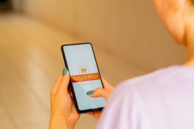 July 12, 2022, Brazil. In this photo illustration, a woman holds a smartphone with the Royal Mail logo displayed on the screen