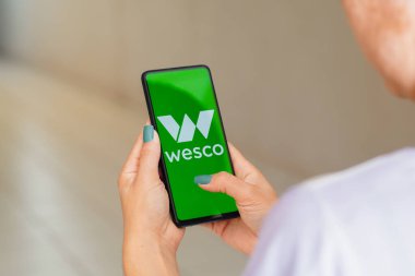 July 12, 2022, Brazil. In this photo illustration, a woman holds a smartphone with the WESCO International logo displayed on the screen