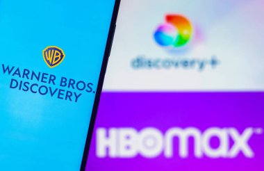 August 5, 2022, Brazil. In this photo illustration, the Warner Bros. Discovery logo is displayed on a smartphone screen and in the background, the HBO Max and Discovery Plus logos