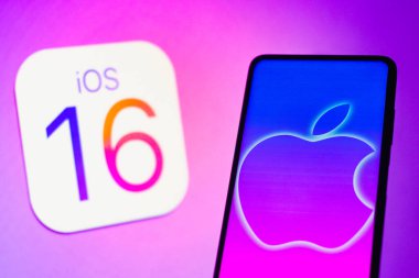 13 Eylül 2022, Brezilya. Bu resimde Apple logosu akıllı bir telefonda ve arka planda iOS 16 işletim sistemi logosunda görüntülendi.