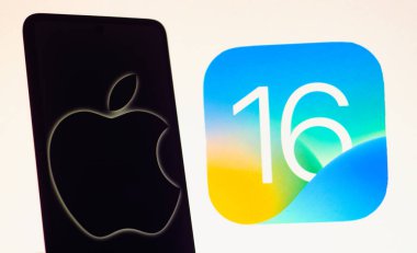 13 Eylül 2022, Brezilya. Bu resimde Apple logosu akıllı bir telefonda ve arka planda iOS 16 işletim sistemi logosunda görüntülendi.