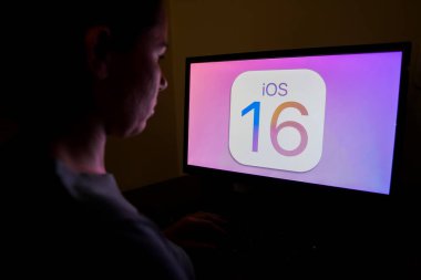 13 Eylül 2022, Brezilya. Bu resimde, bir kadın Apple sistem logosu olan bilgisayara bakıyor, iOS 16 ekranda gösteriliyor