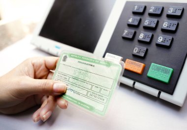2 Ekim 2022, Brezilya. Bu fotoğraf illüstrasyonunda Brezilya seçimlerinde zorunlu unsur olan Seçmen Belgesi (Oy Verme Lisansı) bulunur. Arka planda elektronik bir vazo oy sandığı var.