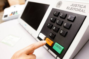 2 Ekim 2022, Brezilya. Bu fotoğraf illüstrasyonunda, Brezilya 'da seçimlerde kullanılan elektronik oy sandığı (oy sandığı) içinde oy kullanma simülasyonunu bir kişi yapar. Turuncu 