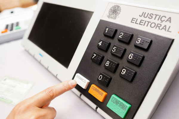 2 октября 2022 года, Бразилия. На этой фотографии человек имитирует голосование в электронном ящике для голосования (урне для голосования), цифровом устройстве для голосования в Бразилии, используемом на выборах. Она нажимает "белый" ключ