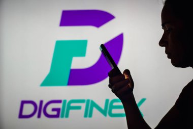 10 Ekim 2022, Brezilya. Bu resimde, bir kadının siluetinde arka planda DigiFinex Dijital Varlıklar Borsası logosu olan bir akıllı telefon var.
