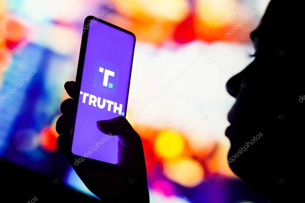 October 17, 2022, Brazil. In this photo illustration, a silhouetted woman holds a smartphone with the Truth Social logo displayed on the screen