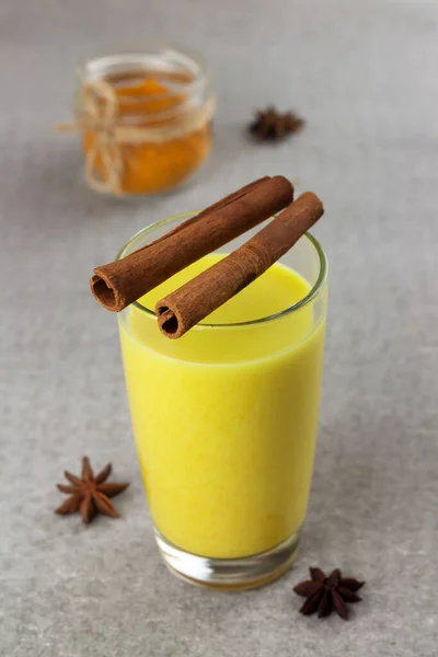 Un vaso de leche dorada, bebida ayurvédica de cúrcuma sobre fondo gris — Foto de Stock
