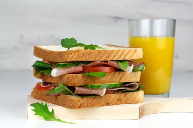 İspanyol jambonlu kulüp sandviçi veya İtalyan jambonu ve bir bardak meyve suyu.