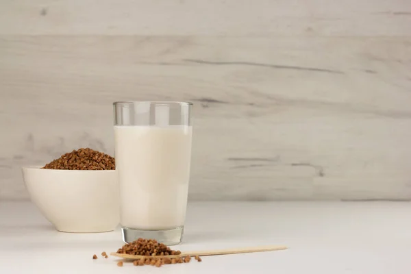 Milchfreie Buchweizenmilch im Glas und Buchweizenkörner in einer Schüssel — Stockfoto