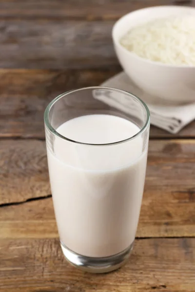 Mléčné bez rýže mléko v brýlích a rýžových zrn v misce na dřevěném pozadí — Stock fotografie