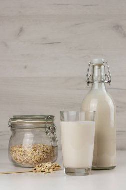 Bir şişe ve bir bardak sütsüz yulaf sütü ve kavanozda gevrek.