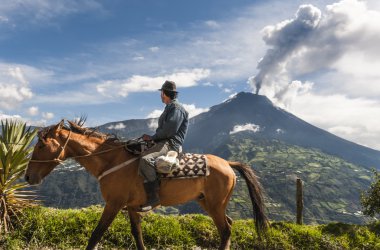 Farmer on a horse looking at the  Tungurahua volcano eruption clipart