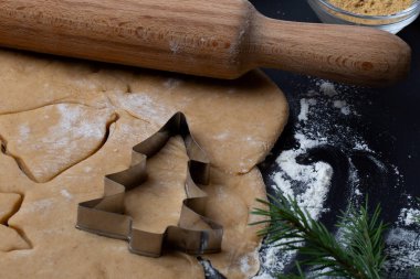 Noel kurabiyesi yapmak için gereken malzemeler: yumurta, un, bal, tarçın, siyah arka planda zencefil