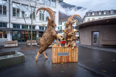 Interlaken, İsviçre - 28 Kasım 2019: Bir Ibex ailesinin peynir fondüsü yiyen ahşap heykeli - Interlaken, İsviçre