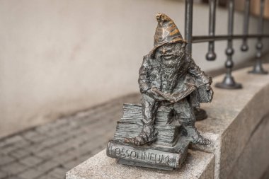 Wroclaw, Polonya - 21 Ağustos 2019: Ossolineum cücesi bir kitap okuyor (Ossolinek) - 2005 yılından beri şehirde yüzlerce wroclaw cüce heykeli belirdi - Wroclaw, Polonya