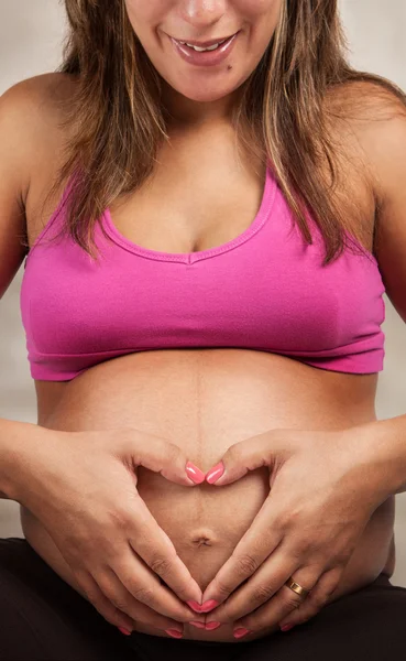 Pregnant Woman showing love making a Heart Shape over her baby inside belly Stock Picture