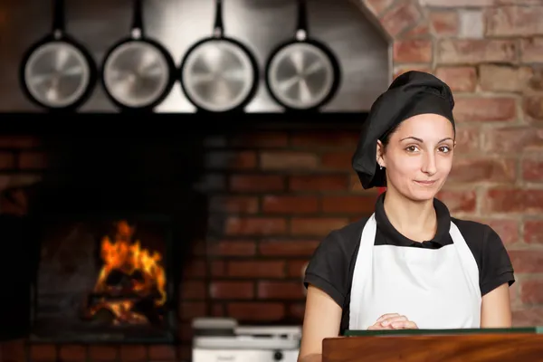 Donna Chef stand in cucina vicino al forno a legna Immagine Stock