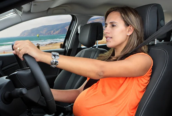 Pregnant Woman Driving a Car on Coastal Road Stock Image