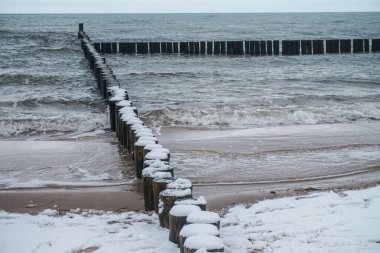 Karla kaplı bir sahilde ahşap damızlık. Kış zamanı.