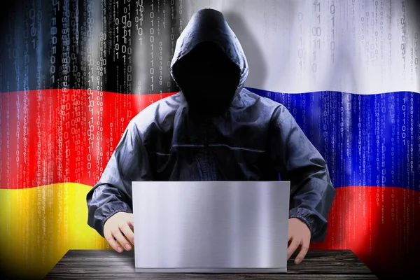 Anonymous hacker working on a laptop, flags of Germany and Russia