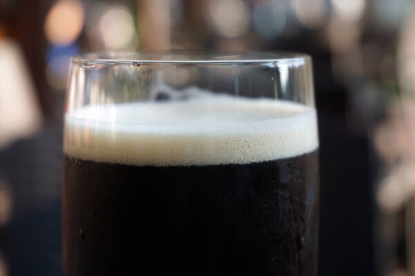 Glass of dark beer, defocused background