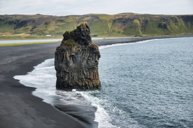 Reynisfjara - black beach in Iceland, single rock and cliffs