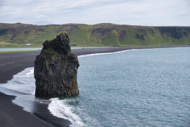 Reynisfjara - black beach in Iceland, single rock and cliffs
