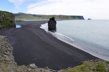 Reynisfjara - black beach in Iceland, single rock and cliffs