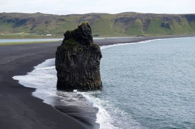 Reynisfjara - black beach in Iceland, single rock and cliffs
