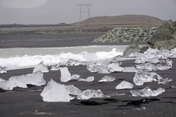 Blocks of ice laying on black volcanic sand - Diamond Beach, Jokulsarlon, Iceland