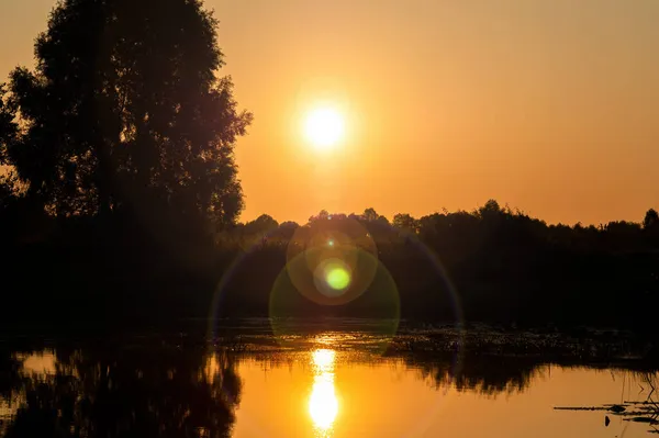 Над водной поверхностью озера пронесся оранжевый солнечный свет. — стоковое фото