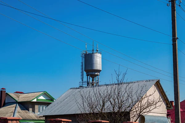 Vodárenská věž nad střechami venkovských domů proti modré obloze. — Stock fotografie