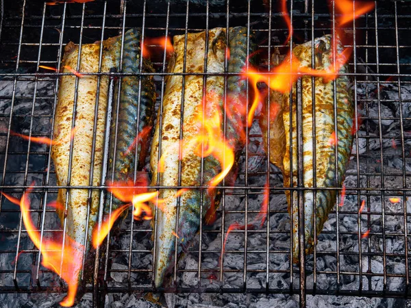 Makrela se peče na kovovém grilu v ohnivém plameni. — Stock fotografie