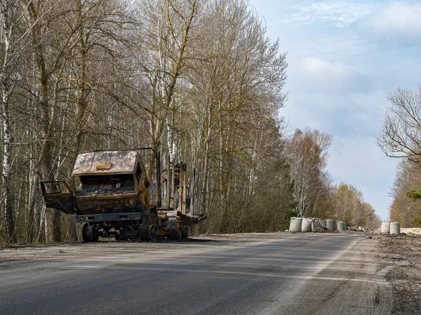 Road traffic accident of a car with fire. Car accident. Road in the forest. Damaged transport. Asphalt pavement. Traffic Laws. Military actions. Motor vehicle. Ukraine.
