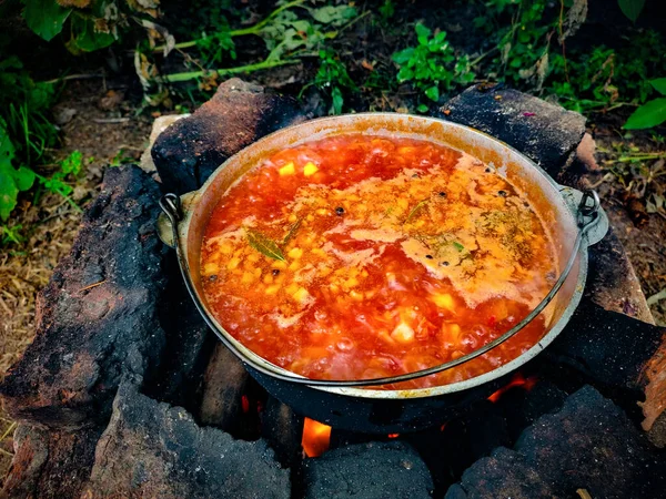 Culinary dish of the national cuisine of Ukraine red borscht. Red Ukrainian borscht. National Ukrainian cuisine. Cooking outside. Food in a wood-burning brick oven. First course.