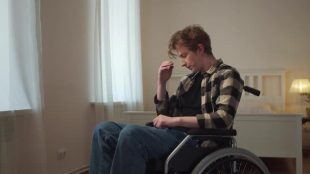 Mladý zdravotně postižený muž jezdí na svém invalidním vozíku po místnosti — Stock video