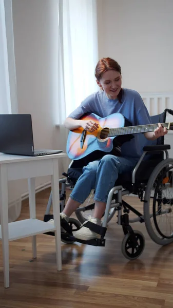 Una mujer discapacitada está aprendiendo a tocar la guitarra en Internet — Foto de Stock
