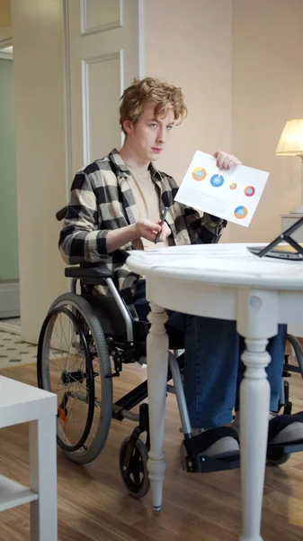 Un joven discapacitado está hablando con alguien y mostrando diagramas — Foto de Stock
