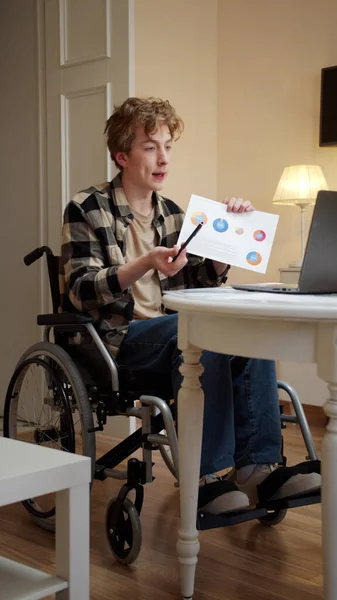 A disabled young man is talking with someone and showing diagrams — Stock Photo, Image