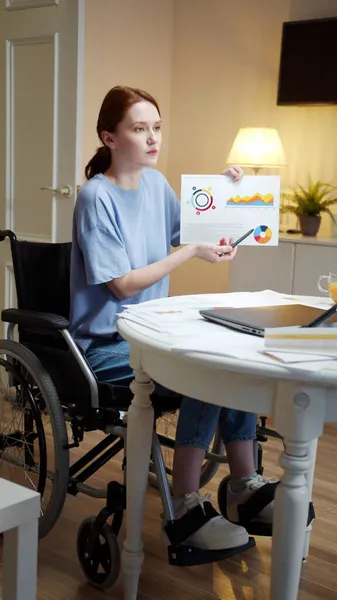 Una joven discapacitada está hablando con alguien y mostrando diagramas — Foto de Stock