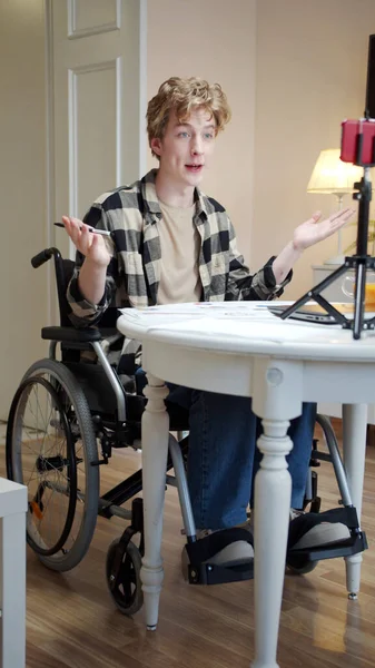 Un joven discapacitado está saludando a alguien en Internet y mostrando cartas — Foto de Stock