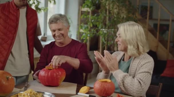 Семья аплодирует и радуется, что дедушка испек тыкву на Хэллоуин — стоковое видео