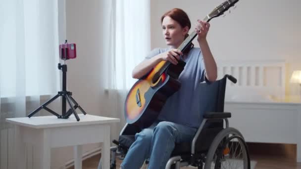 Een jonge gehandicapte dame vertelt over de gitaar en bereidt zich voor om te spelen — Stockvideo