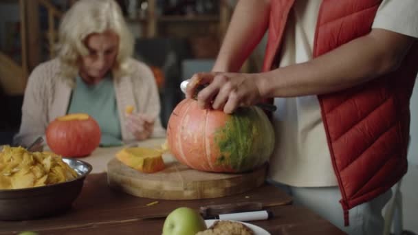 Rodzina siedzi przy stole i wyciąga miąższ z dyni i rzeźbi lampy na Halloween — Wideo stockowe