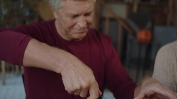 Старий робить дірку в гарбузі з ножем — стокове відео