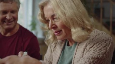 Yaşlı bir kadın balkabağını keçeli kalemle çiziyor. Gülümsüyor ve eğleniyor.