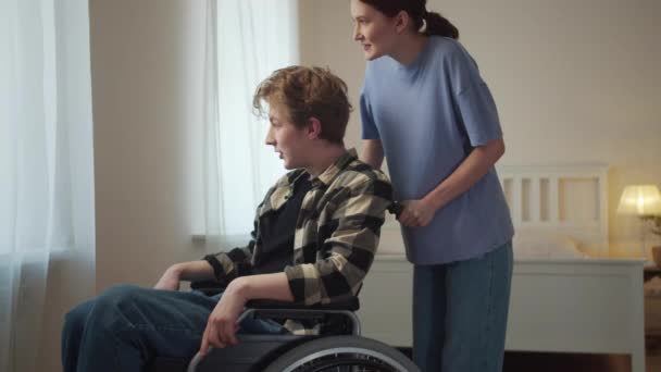 Een vrouw rijdt met haar vriend in een rolstoel. — Stockvideo