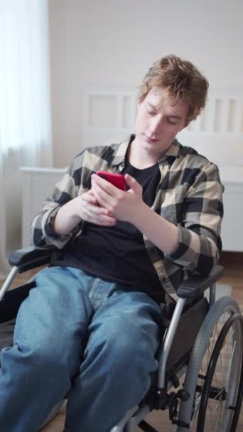 Un disabile è seduto sulla sua sedia a rotelle e guarda attraverso Internet — Video Stock